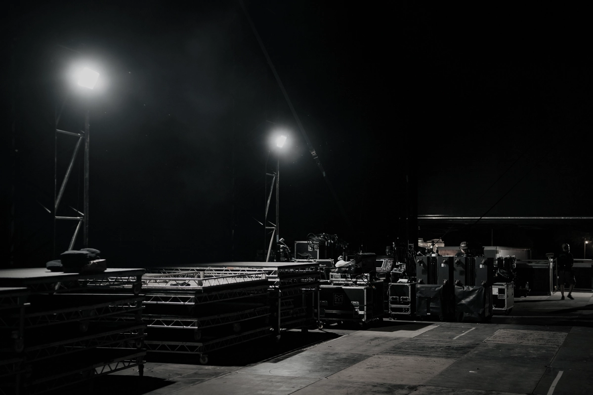 A floodlit apron at night, with staged cargo and ground equipment under two light masts.