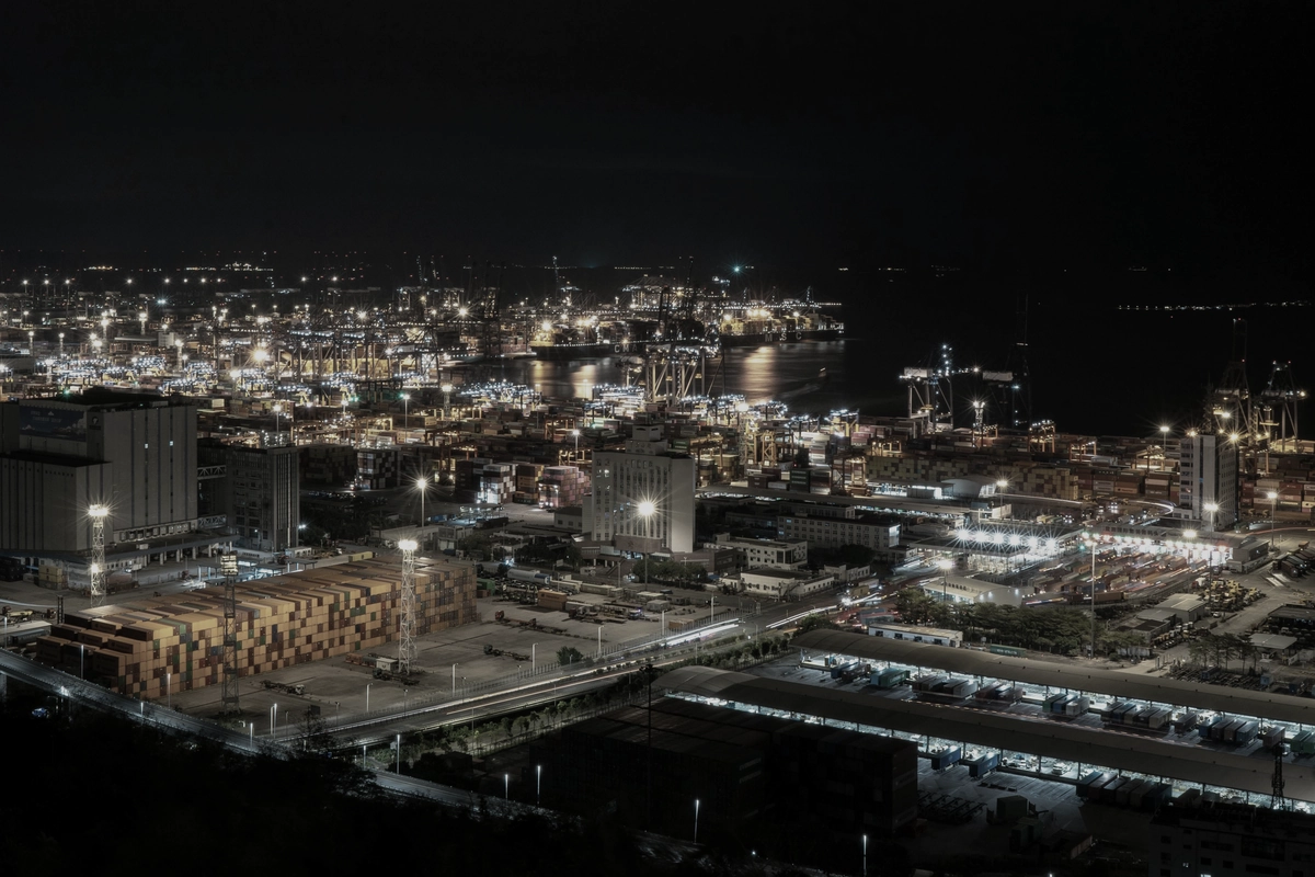 An industrial port at night seen from high above, its quays and yards lit up.